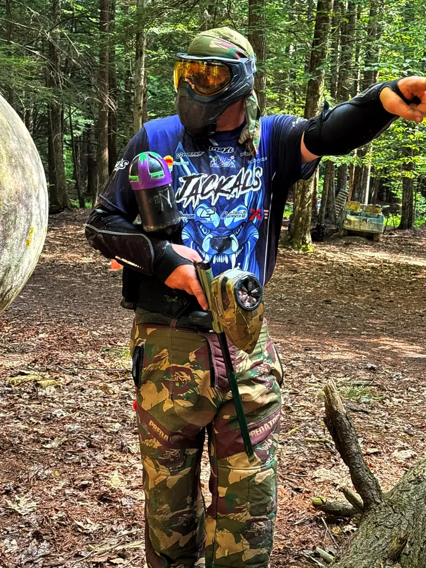 Player in a blue Jackals jersey pointing downfield on a wooded trail