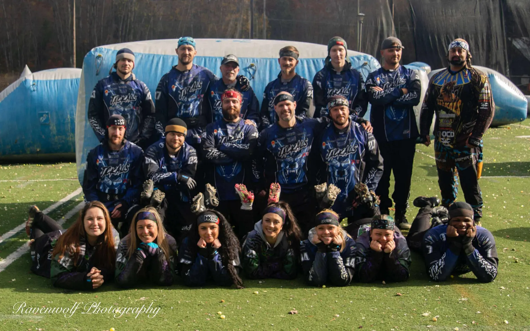 The 2025 Triple A Jackals team photo on the turf speedball field, with players in blue Jackals jerseys standing, kneeling, and lying in front of an inflatable bunker
