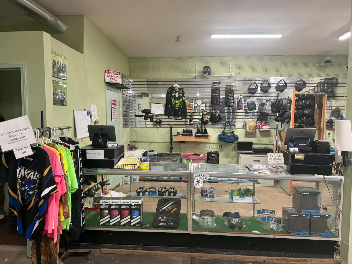 Triple A pro shop counter with display cases of goggles and gear and a rack of shirts and jerseys