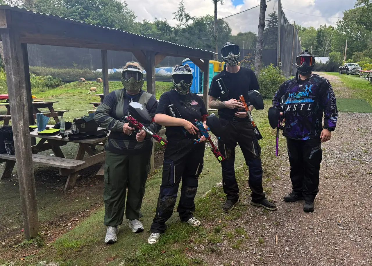 Four geared-up players with their markers by the covered staging area at Triple A