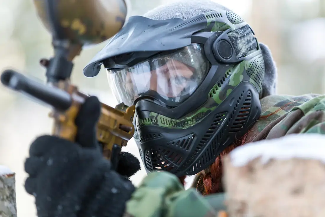 Player in a camo mask and goggles aiming a marker on a cold day
