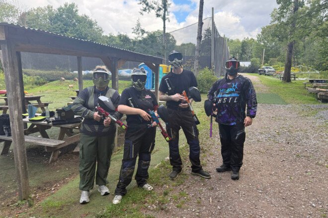 Four masked players holding their markers beside the covered picnic area at Triple A